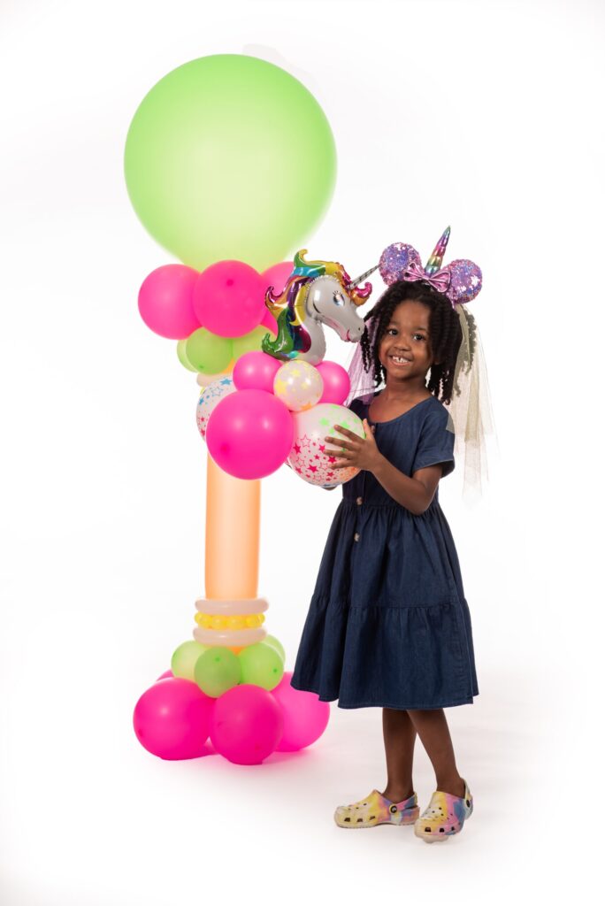 Child with unicorn birthday balloon arch